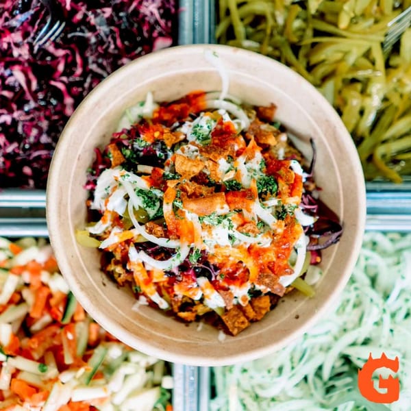 A Gita Pita Mediterranean bowl with various toppings, sauces, and fresh ingredients.