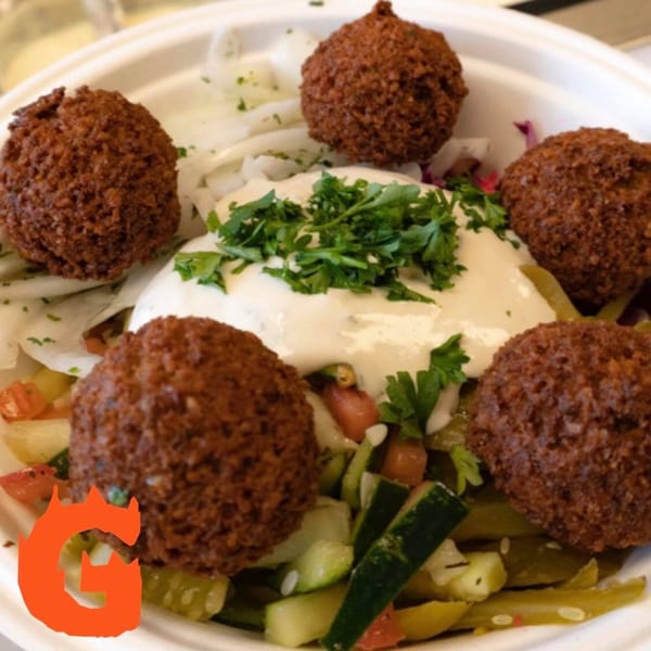 Gita Pita falafel bowl with five falafel, white sauce, parsley, and chopped vegetables.